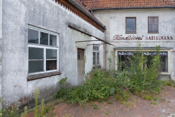 View of an overgrown forecourt and shop window of an abandoned bakery, Barrien, Syke, Diepholz,
