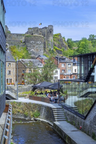 Tourists at restaurant along the river Ourthe and ruined castle in the city La Roche-en-Ardenne,