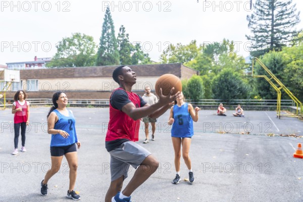 Group of diverse basketball players enjoying a lively game on an outdoor court, highlighting