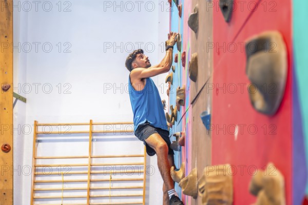 Young sportsman ascending a vibrant climbing wall, showcasing strength, agility, and intense focus