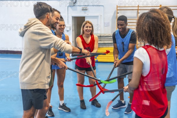 Floorball players gathering their sticks in a circle before a match, smiling and displaying