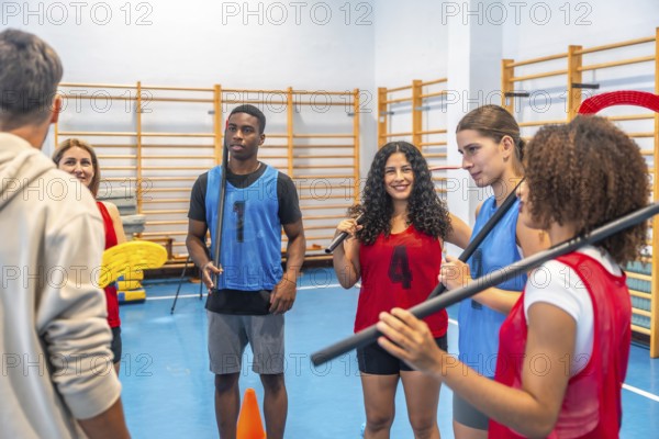 Multi ethnic floorball team gathered in a gym, attentively listening to their coach's instructions