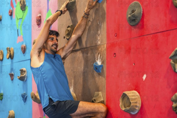 Focused male athlete ascends a vibrant indoor climbing wall, demonstrating strength, agility, and