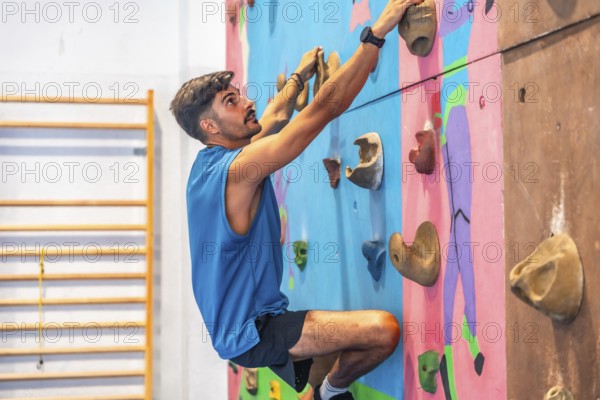 Young male athlete ascending an indoor climbing wall, demonstrating strength, agility, and focus in