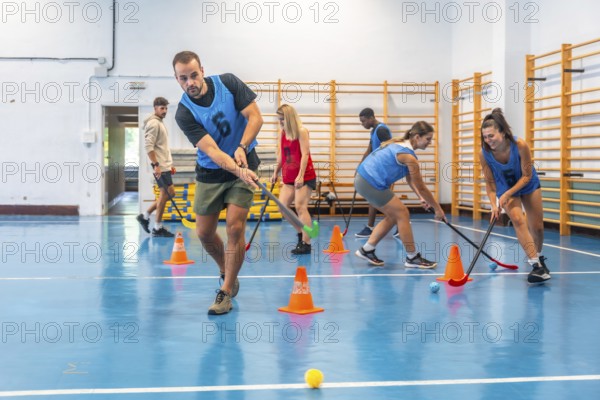 Group of athletes engaged in an intense floorball training session, skillfully dribbling the ball