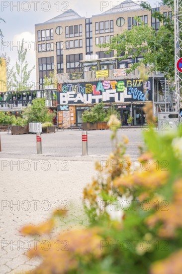 Building with urban graffiti 'Nothing Lasts But the Beautiful' and flowers, Werksviertel Munich,