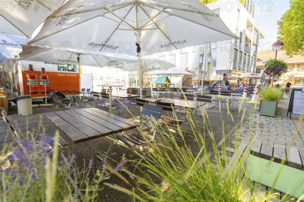Empty outdoor café with wooden tables, chairs and parasols in a sunny city neighbourhood,