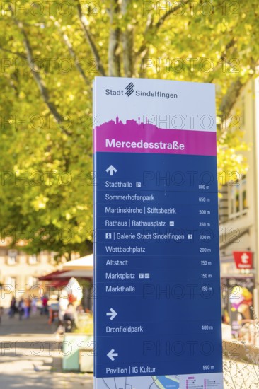 Urban signpost with various destinations, surrounded by trees under a sunny sky, Sindelfingen,