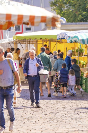 A busy outdoor market with lots of people and colourful stalls under parasols, Sindelfingen,