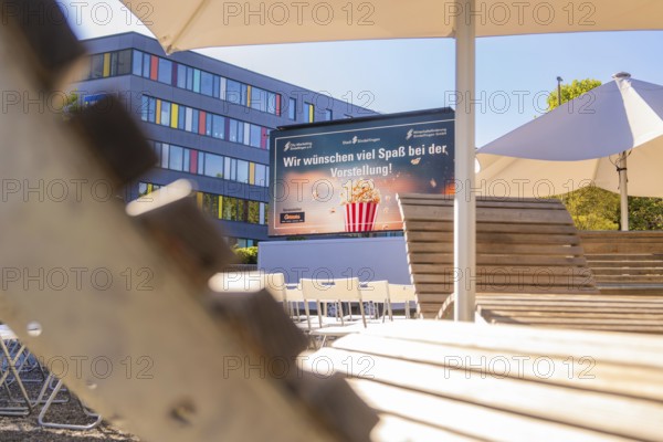 An urban outdoor area with chairs and a screen under parasols, open air cinema Sindelfingen,