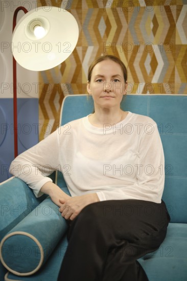 A woman relaxes on a vibrant blue sofa, surrounded by decorative walls featuring geometric patterns