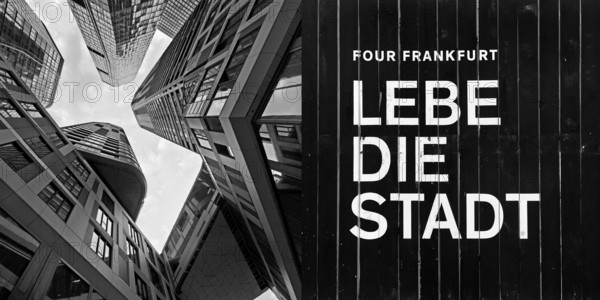 Frog's-eye view of skyscrapers in the banking district and construction fence with the inscription