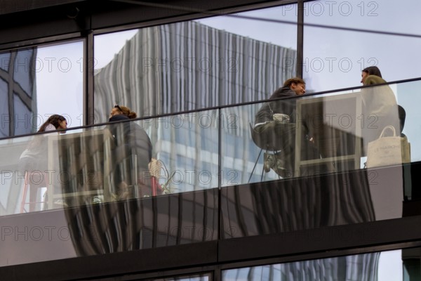 People on the glazed outdoor balcony in a bar with reflection of a skyscraper, Frankfurt am Main,