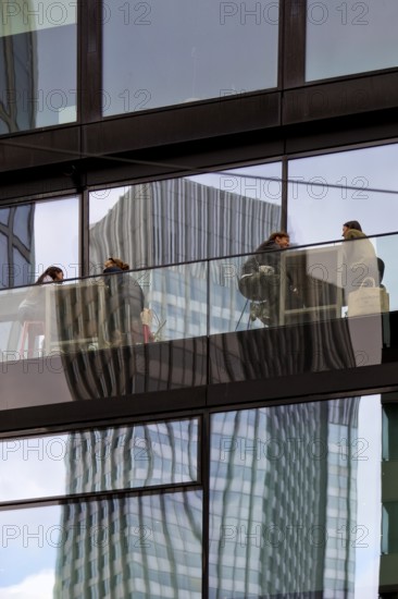 People on the glazed outdoor balcony in a bar with reflection of a skyscraper, Frankfurt am Main,