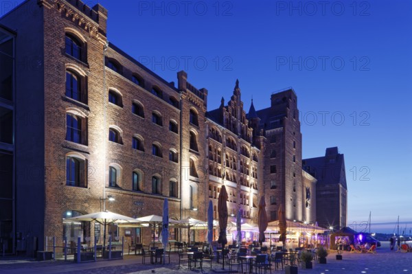 Night shot, outdoor seating, sunshades, restaurant, illuminated, romantic scenery behind, building,