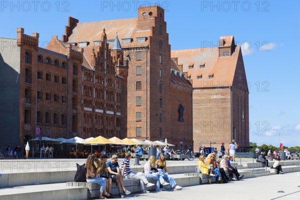 Visitors sitting and strolling along the waterfront promenade, warehouse building in the