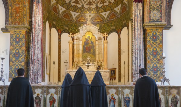 Many monks stand in front of an elaborately decorated altar with bright ornaments, Inside the