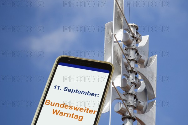 (Photomontage) Close-up of a siren, next to it an open smartphone with text 11 SEPTEMBER: FEDERAL