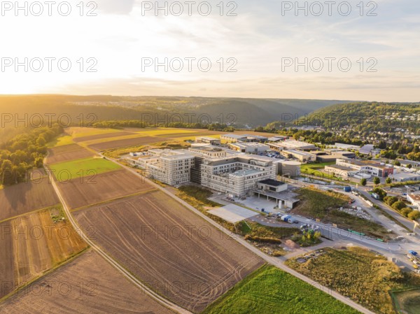 Extensive landscape with a modern building surrounded by fields and hills, new hospital building,