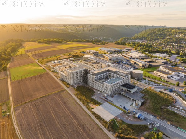 Modern building surrounded by fields and surrounding hills at sunset, new hospital building, Calw