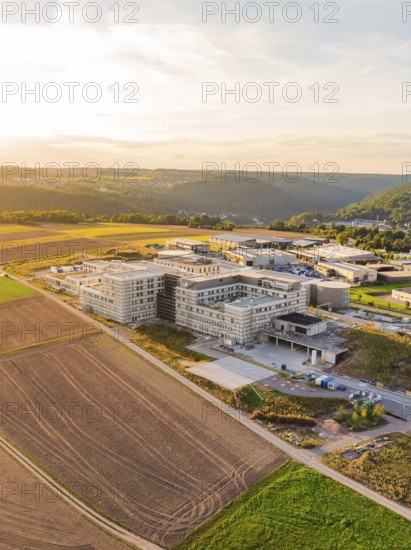Large building in a rural setting with fields and rolling hills at dusk, new hospital building,
