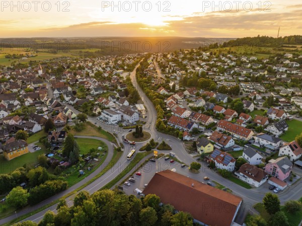 Sea of houses with curved streets in warm sunset light and green surroundings, small town of Perle