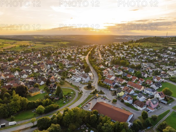 Urban landscape with houses and streets in gentle evening sun, surrounded by hills, small town