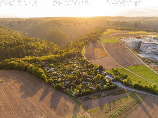 Campsite on the edge of a forest with farmland in the warm light of the setting sun, small town of