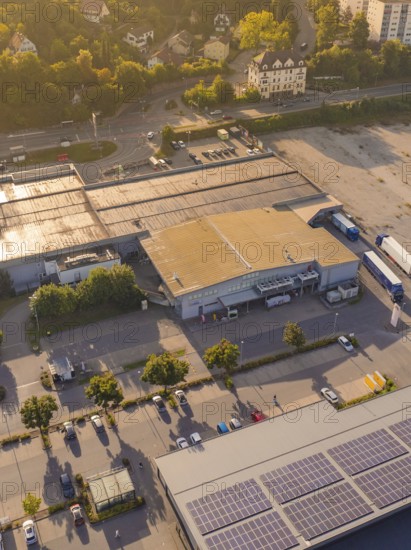 Industrial buildings at dusk with solar panels on the roof and car parks, small town of Perle