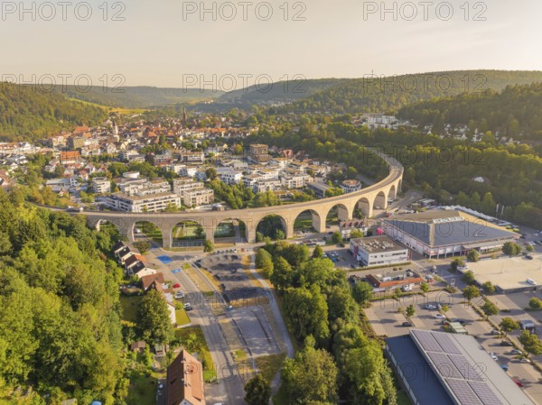 Large viaduct leading over a town and through a hilly landscape, shown from the air, small town of