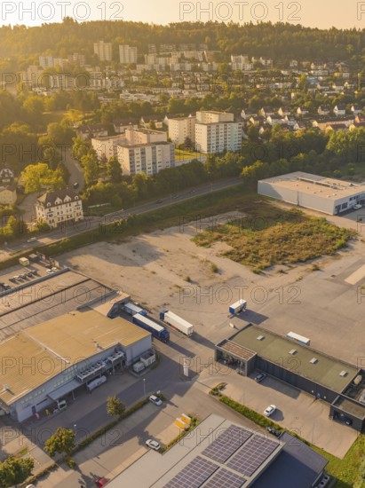 Industrial and residential area at dusk with surrounding nature and urban development, small town