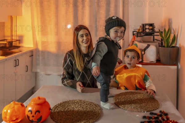 Mother and children enjoying halloween costumes, playing and laughing together in the cozy kitchen,