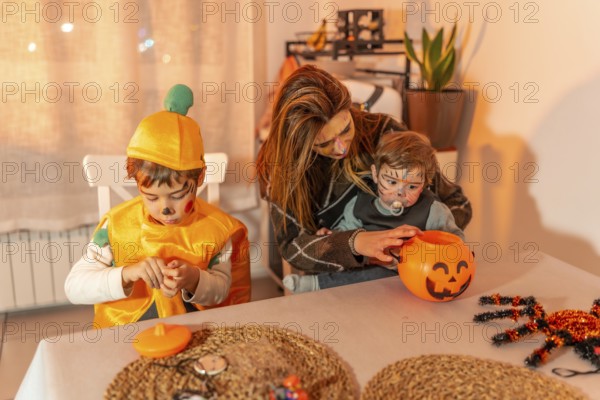 Mother and children wearing festive halloween costumes, joyfully preparing treats together at home,