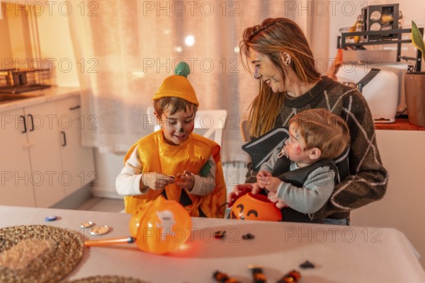 Mother and children wearing halloween costumes are sitting at the kitchen table and preparing for