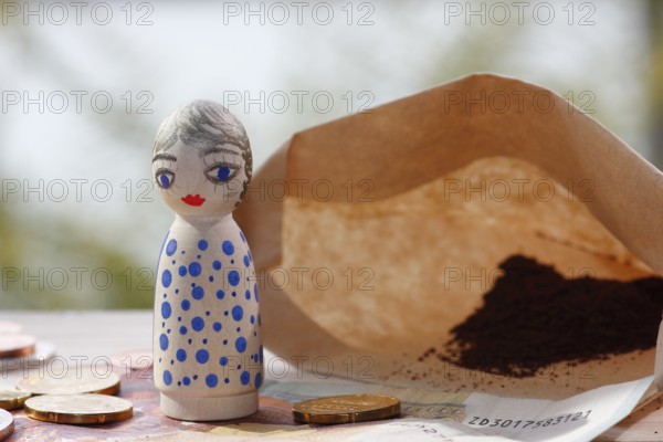 Pretty female wooden cone figure with coins and banknote in front of filter bag with coffee North