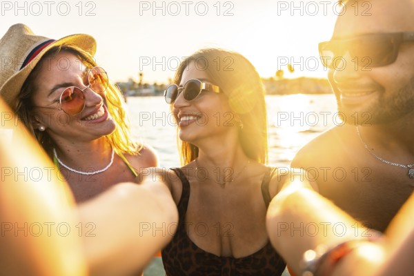 Group of friends enjoying a scenic boat trip, capturing joyful selfies against a stunning sunset
