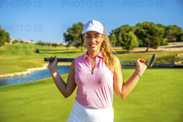 Young golfer woman holding golf club behind her shoulders smiling on a sunny day on a beautiful