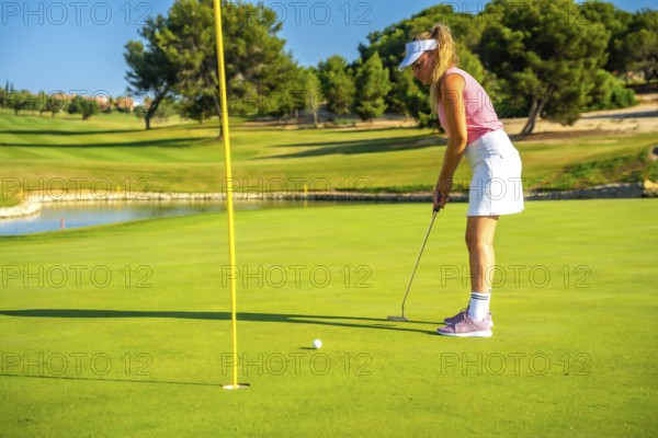 Professional golfer putting the ball on a sunny day, enjoying the beautiful scenery of a lush golf