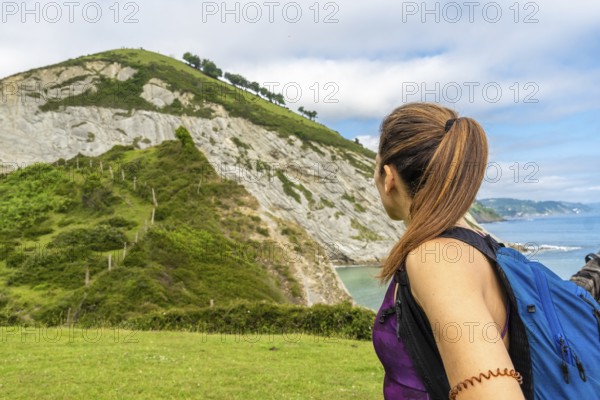 Female tourist with backpack admiring the coastal landscape of sakoneta beach and its flysch