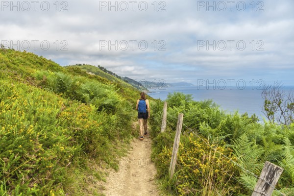 Female tourist enjoying a picturesque hike along the cliffs leading to sakoneta beach in zumaia,