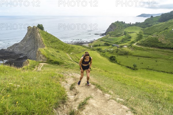 Tired athlete taking a break during trail running workout along the picturesque cliffs of zumaia,