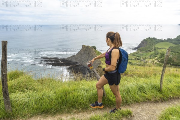 Female hiker admiring the impressive flysch cliffs and coastline of sakoneta beach in zumaia,