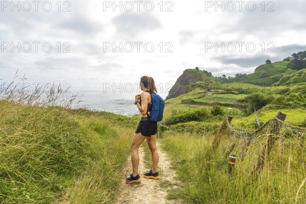 Female hiker enjoying the scenic view of sakoneta beach and its flysch cliffs in zumaia, gipuzkoa,