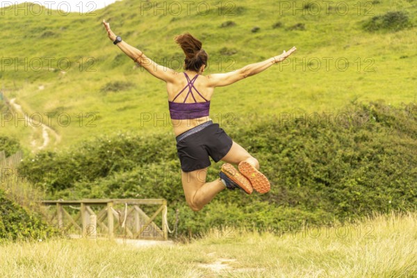 Runner celebrates reaching the top of a hill overlooking sakoneta beach and the flysch cliffs in