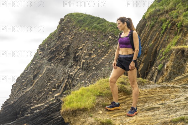 Female hiker admiring the breathtaking flysch cliffs at sakoneta beach in zumaia, gipuzkoa, a