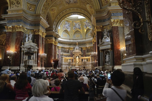 Tourists and locals are attending a mass in st. Stephen's basilica, a romanesque catholic basilica