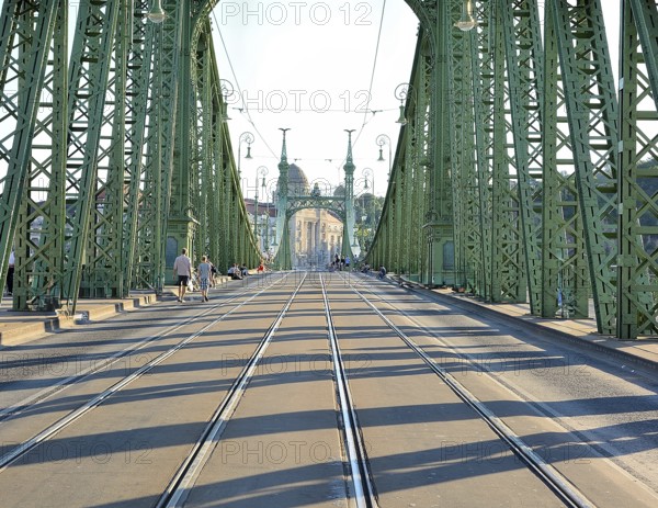 Tourists walking on liberty bridge in budapest, hungary, on a sunny day, with its iconic green