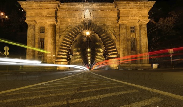 Long exposure photo of cars driving into a tunnel in budapest at night, creating streaks of light