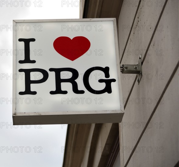 White square sign with i love prg written on it, hanging on a building facade, expressing affection