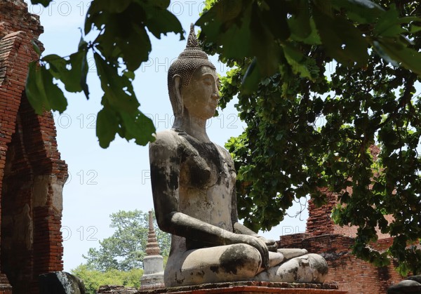 Serene buddha statue sits in peaceful meditation amidst crumbling temple ruins, showcasing